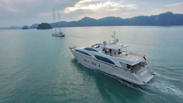 Aerial view of a motor yacht under way past a sailing yacht lying at anchor