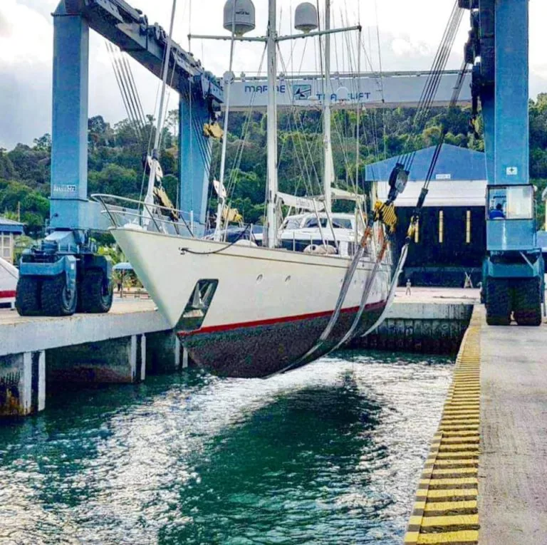Sailing yacht lifted clear of the water in the slings of a travel lift