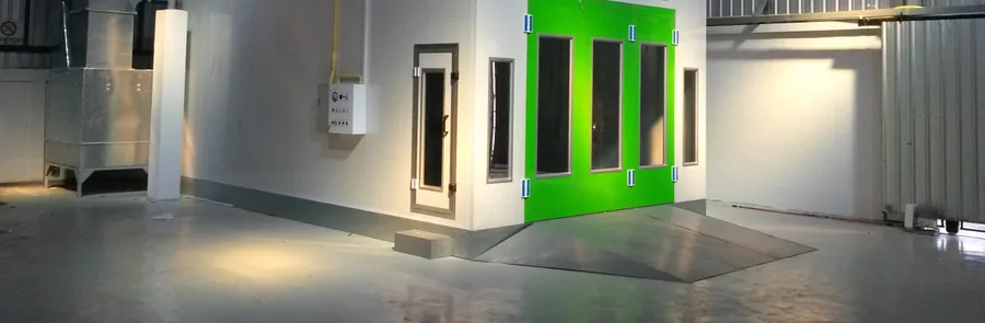 Enclosed spray booth in a marine paint shop, with extraction ducting and a roll-in ramp